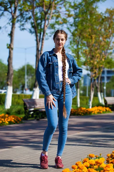 Красива дівчина в джинсовій куртці сидить на лавці в літній парі — стокове фото