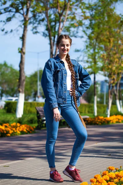 Девушка в джинсовой куртке сидит на скамейке в летнем парике — стоковое фото