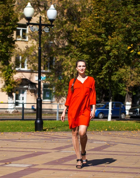 Jonge mooie vrouw in rode jurk wandelen in de zomer straat — Stockfoto