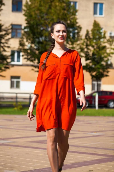 Young beautiful woman in red dress walking in summer street — Stock Photo, Image
