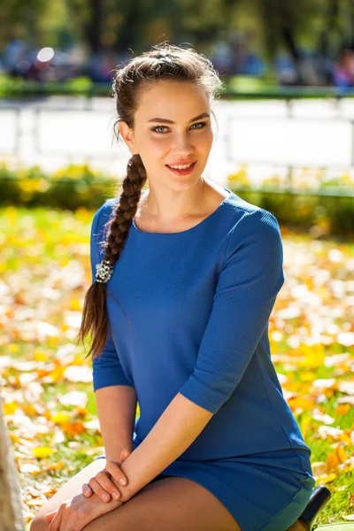 Νέα όμορφη μελαχρινή γυναίκα με μπλε φόρεμα στο φθινόπωρο πάρκο — Φωτογραφία Αρχείου