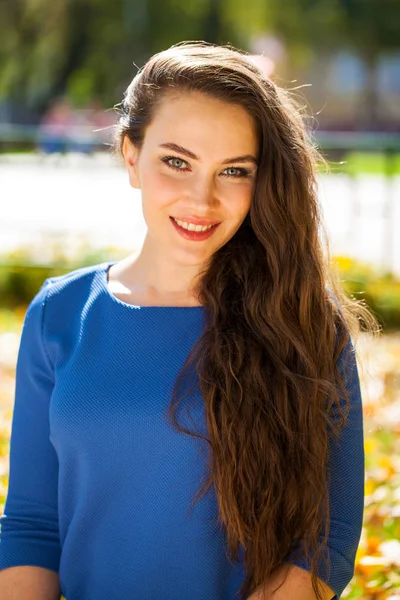 Young beautiful brunette woman in blue dress in autumn park — Stock Photo, Image