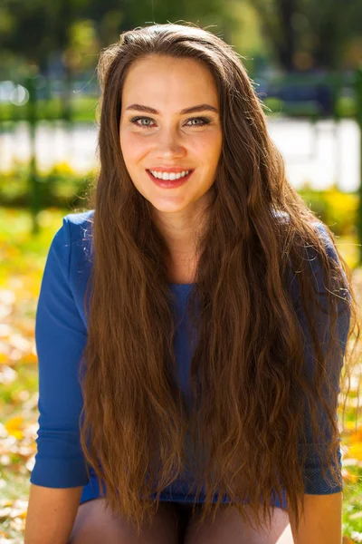 Young beautiful brunette woman in blue dress in autumn park — Stock Photo, Image