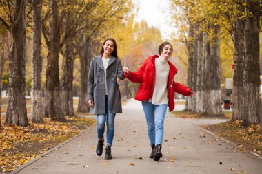 Gri yün ceketli ve kırmızı ceketli iki kız arkadaş. 