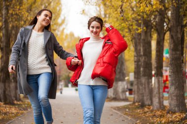 Gri yün ceketli ve kırmızı ceketli iki kız arkadaş. 