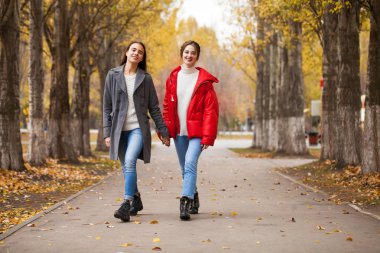 Gri yün ceketli ve kırmızı ceketli iki kız arkadaş. 