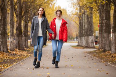 Gri yün ceketli ve kırmızı ceketli iki kız arkadaş. 
