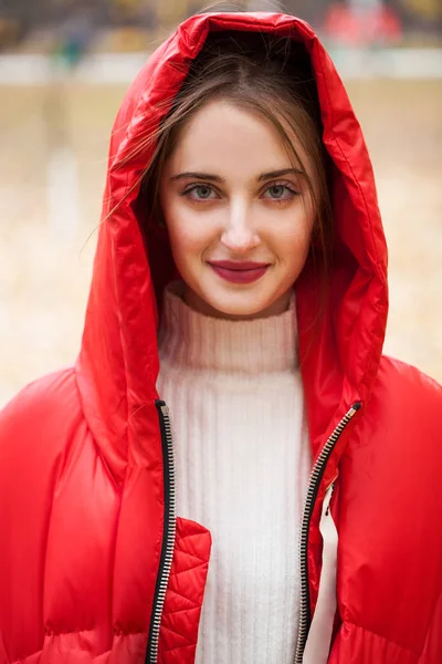 Sonbaharın arka planında poz veren kırmızı ceketli genç bir kadın. — Stok fotoğraf