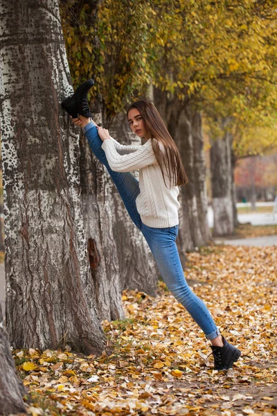 Beyaz yün kazaklı ve kot pantolonlu genç bir kadın. — Stok fotoğraf