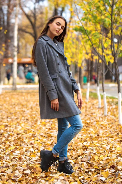 Retrato de una joven hermosa niña en jeans azules y abrigo gris — Foto de Stock