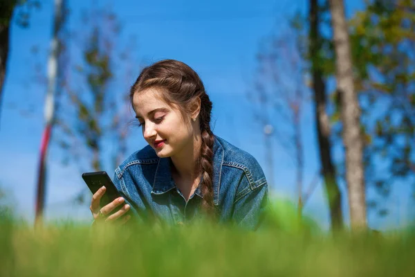 Mooie jonge brunette vrouw liggend op het groene gras — Stockfoto