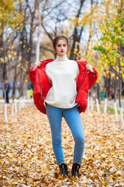 Młoda piękna dziewczyna w niebieskich dżinsach i czerwony dół kurtka pozowanie w — Zdjęcie stockowe