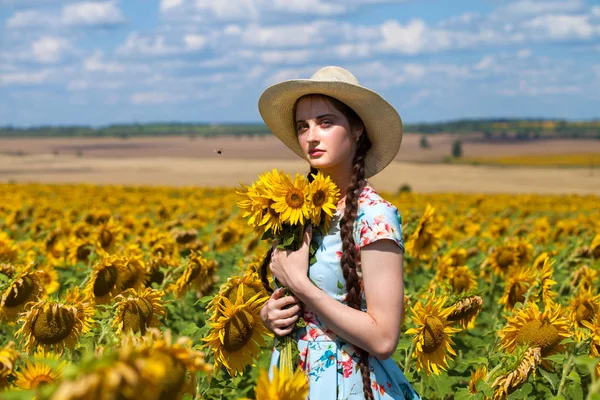 Retrato de una joven hermosa en un campo de girasoles — Foto de Stock