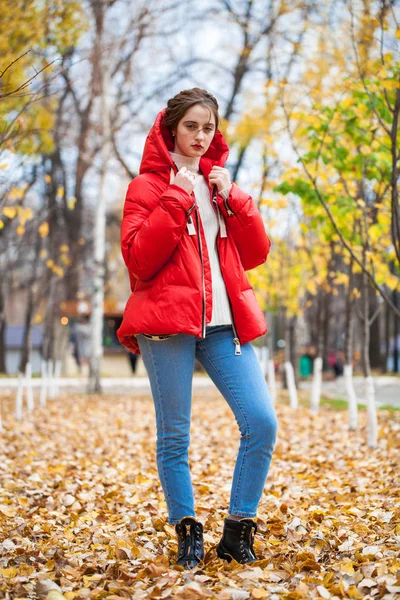 Joven hermosa chica en pantalones vaqueros azules y chaqueta roja posando en — Foto de Stock