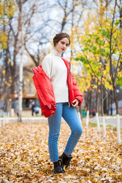 Joven hermosa chica en pantalones vaqueros azules y chaqueta roja posando en — Foto de Stock