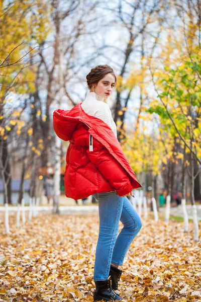 Joven hermosa chica en pantalones vaqueros azules y chaqueta roja posando en — Foto de Stock