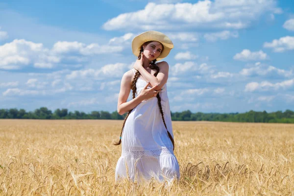 Jovem morena de vestido branco andando em um campo de trigo — Fotografia de Stock