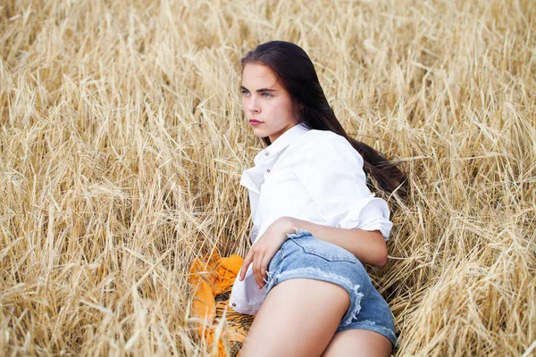 Ung brunette kvinde i hvid skjorte og blå jeans shorts - Stock-foto