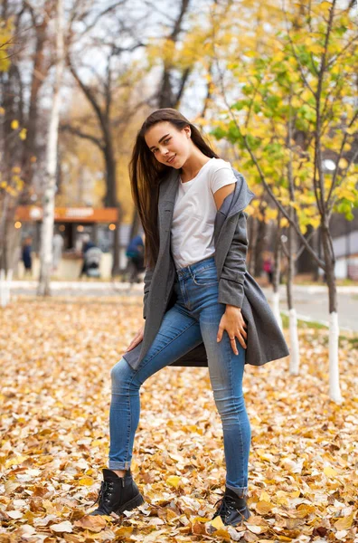 Retrato de una joven hermosa niña en jeans azules y abrigo gris — Foto de Stock