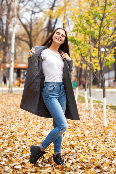 Portrait of a young beautiful girl in blue jeans and gray coat — Stock Photo, Image
