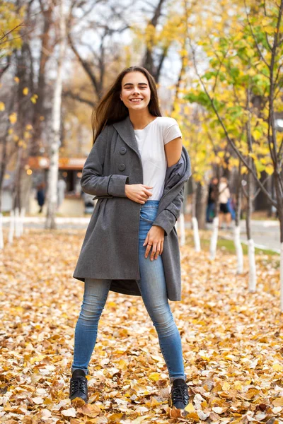 Portrait d'une jeune belle fille en jean bleu et manteau gris — Photo