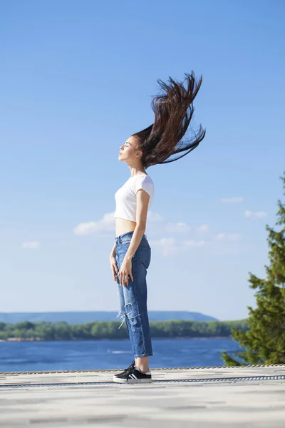 Piękna Brunetka kobieta pozowanie przeciwko błękitne niebo jasne słonecznie — Zdjęcie stockowe