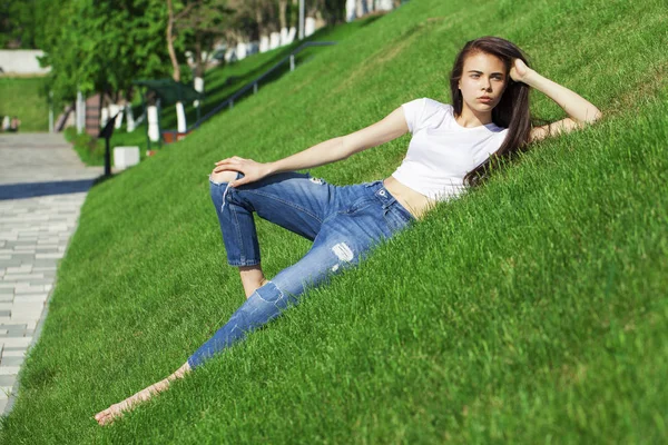 Retrato de una joven hermosa niña descansando en el césped en el pa —  Fotos de Stock