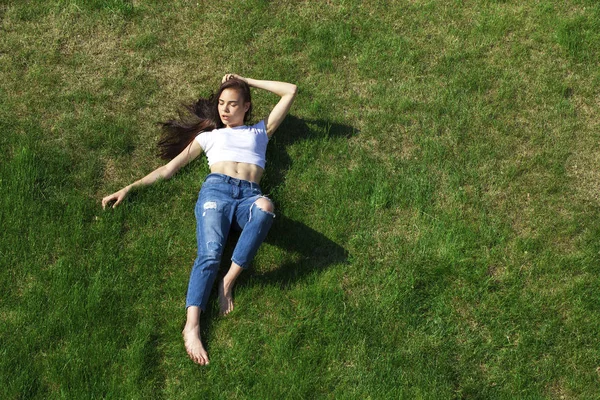 Retrato de una joven hermosa niña descansando en el césped en el pa — Foto de Stock