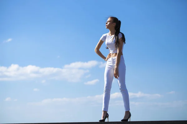 Beautiful brunette woman posing against blue sky bright sunny we — Stock Photo, Image