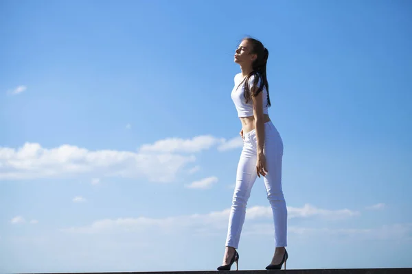 Schöne brünette Frau posiert vor blauem Himmel strahlend sonnig wir — Stockfoto