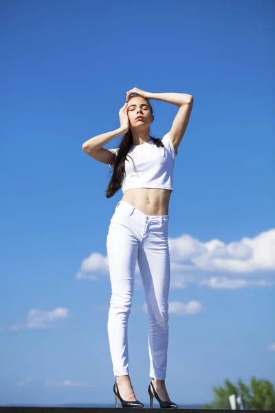 Hermosa mujer morena posando contra el cielo azul brillante soleado nosotros —  Fotos de Stock