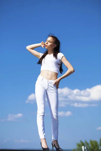 Hermosa mujer morena posando contra el cielo azul brillante soleado nosotros —  Fotos de Stock