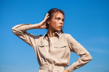 Bej elbiseli güzel esmer kız arkaya karşı poz