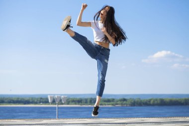 Genç güzel esmer kadın mavi gökyüzüne karşı poz veriyor.