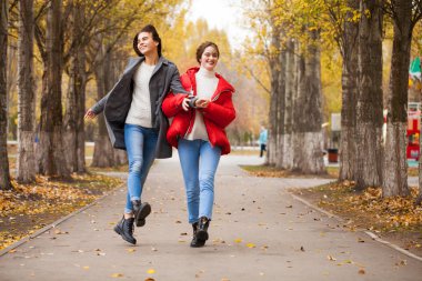 Gri yün ceketli ve kırmızı ceketli iki kız arkadaş. 