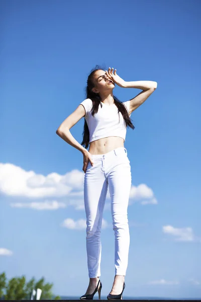 Beautiful brunette woman posing against blue sky bright sunny we — Stock Photo, Image