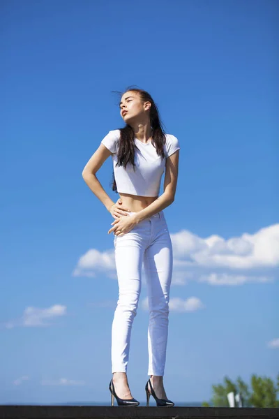 Beautiful brunette woman posing against blue sky bright sunny we — Stock Photo, Image