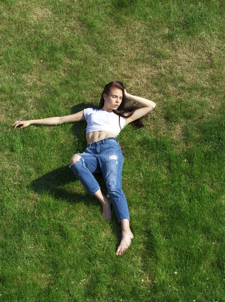 Retrato de una joven hermosa niña descansando en el césped en el pa — Foto de Stock