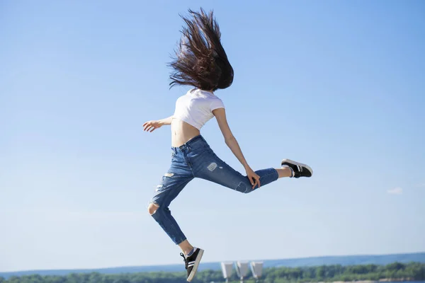 Joven hermosa morena posando contra el cielo azul brillante su —  Fotos de Stock