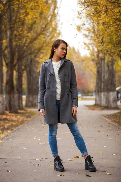 Retrato de una joven hermosa niña en jeans azules y abrigo gris —  Fotos de Stock