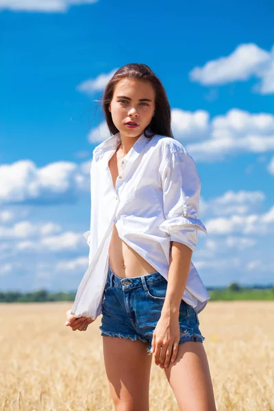 Mladá brunetka v bílé košili a modré džíny — Stock fotografie
