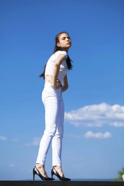 Bella donna bruna in posa contro il cielo blu luminoso soleggiato noi — Foto Stock