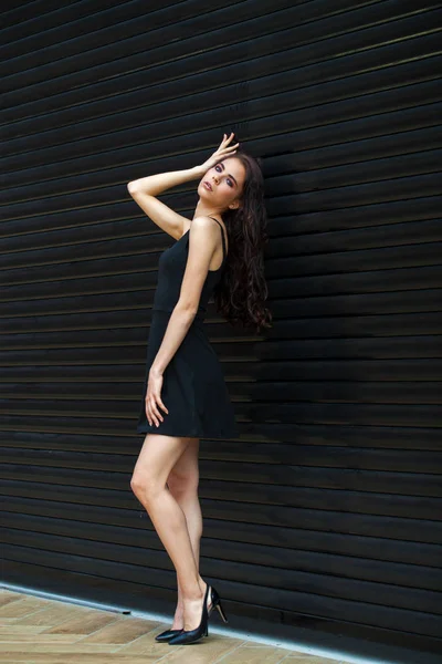 Morena mujer joven en sexy vestido negro, estudio de la pared interior — Foto de Stock