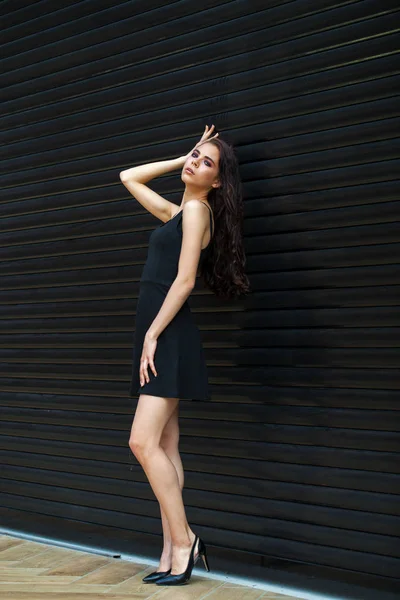 ブルネット若いです女性でセクシー黒ドレス,スタジオ壁室内 — ストック写真
