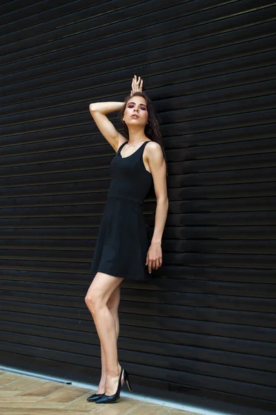 Brunette young woman in sexy Black dress, studio wall indoor — Stock Photo, Image