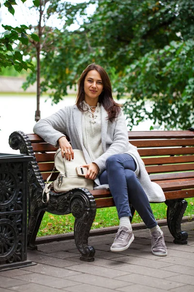 Young beautiful woman sitting on a bench in the autumn park — Stock Photo, Image