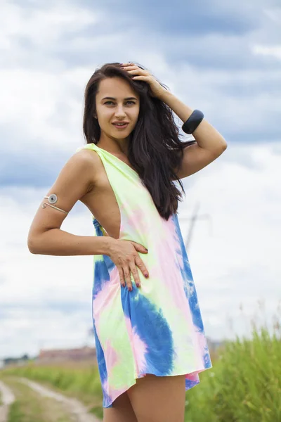 Young beautiful woman in colored tunic posing against the backgr — Stock Photo, Image
