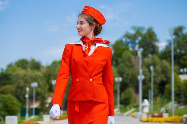 Beautiful stewardess dressed in official red uniform gainst a bl clipart