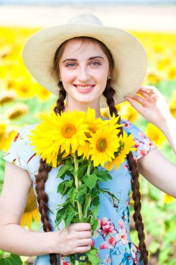 Ayçiçeği tarlasında hasır şapkalı güzel bir kadın.