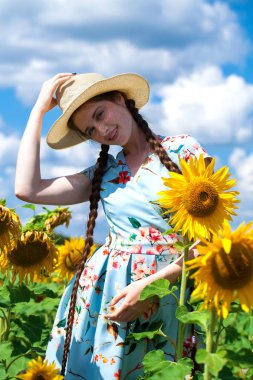 Ayçiçeği tarlasında hasır şapkalı güzel bir kadın.